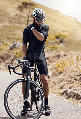 Buy stock photo Male cyclist holding his shoulder in pain while suffering from a sports injury while cycling or training on a mountain road. Fit and active man wearing sports gear while exercising