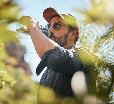 Buy stock photo One mature caucasian man taking a break to drink water while hiking alone in the woods. Fit and active male getting thirsty on a trek while exploring an adventure and the beauty of nature alone