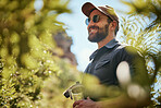 Fit adventurous man wearing glasses and a cap while out hiking or exploring the woods. Handsome man with beard smiling while exploring nature in the forest