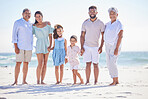 Multi generation family on holding hands while standing on the beach together. Mixed race family with two children, two parents and grandparents spending time together by the sea