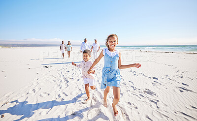 Buy stock photo Portrait of adorable little girl and boy holding hands while running together on sandy beach while family follow in the background. Carefree sibling brother and sister having fun during summer beach vacation with their parents and grandparents family