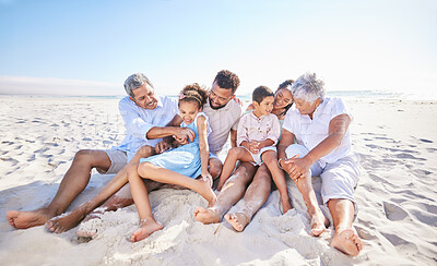 Buy stock photo Carefree three generation family sitting together in the sand while spending time together at the beach. Loving parents and grandparents bonding with two adorable kids while on summer vacation