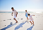 Active father and two children playing soccer on the beach. Single dad having fun and kicking ball with his daughter and son while on vacation by the sea