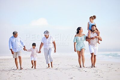 Multi generation family on vacation walking along the beach together. Mixed race family with two children, two parents and grandparents spending time together by the sea