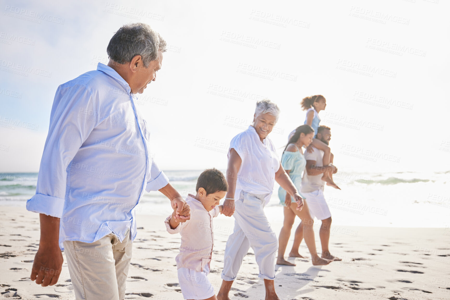 Buy stock photo Big family, vacation and holding hands walking on beach for fun bonding, holiday or weekend together in nature. Grandparents, parents and children on ocean walk by the coast on mockup space outdoors