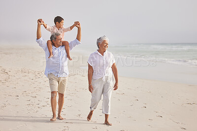 Buy stock photo Happy mixed race grandparents walking on the beach with their grandson. Little boy sitting on his grandfathers shoulders and enjoying summer vacation by the beach