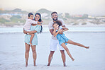 Full length portrait of a happy mixed race family standing together on the beach. Loving parents having fun with their two children during family vacation by the beach