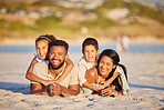 Portrait of a happy mixed race family lying together on the beach. Little girl and boy lying on their parents while having fun and spending time together on vacation
