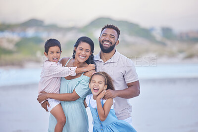 Buy stock photo Portrait of a cheerful mixed race family laughing while standing together on the beach. Loving parents spending time with their two children during family vacation by the beach