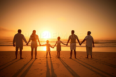 Rear view of multi generation family silhouetted on the beach. Carefree family with two children, two parents and grandparents holding hands and watching the sunset at the beach