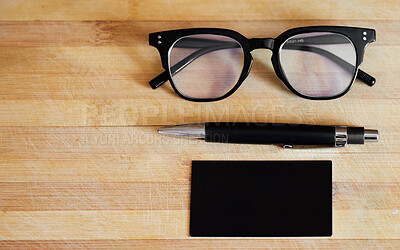 Pics of Above still life flat lay shot of glasses, spectacles, eyewear, a pen and a notepad, notebook on a wooden table, desk in a bright, modern corporate office in a business concept, setting , stock photo, images and stock photography PeopleImages.com.