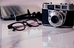 Closeup of a camera and glasses on a desk in an office. Blogger or photographer's workstation at home of in a modern office  