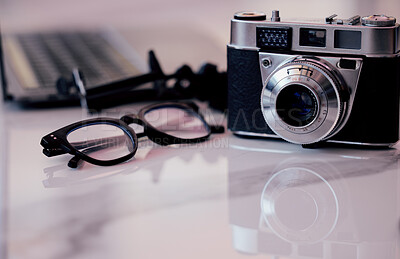 Buy stock photo Closeup, desk and photography studio with camera, glasses and computer for art, journalist or news company. Retro equipment, spectacles and professional lens with laptop in office for newspaper job