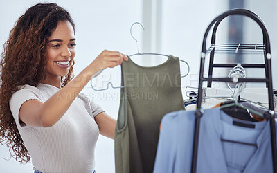 One beautiful hispanic woman checking out clothing while shopping in a retail store. Attractive mixed race female looking for sales while doing some retail therapy. Spending and consumerism