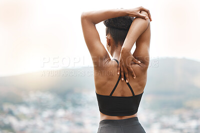 Rearview shot of a young african american female athlete looking at a view while stretching before exercising outside workout. Dedicated black woman warming up before starting her outdoor workout