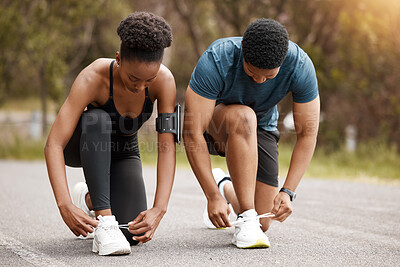 Fit african american couple tying their laces outdoors before a run. Young athletic man and woman training to improve their cardio and endurance for a healthy lifestyle. They love to workout together
