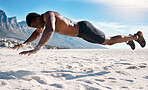 Fit young black man doing plank hold exercises on sand at the beach in the morning. African American muscular male bodybuilder athlete doing bodyweight workout to build a strong core and endurance