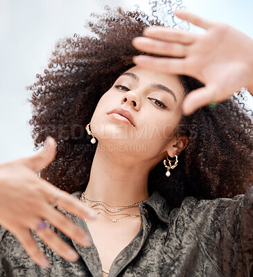 Closeup of a beautiful young mixed race woman with an afro framing her face with her hands. Looking for the perfectly focused portrait shot while taking pictures as a hobby or for a shoot on location