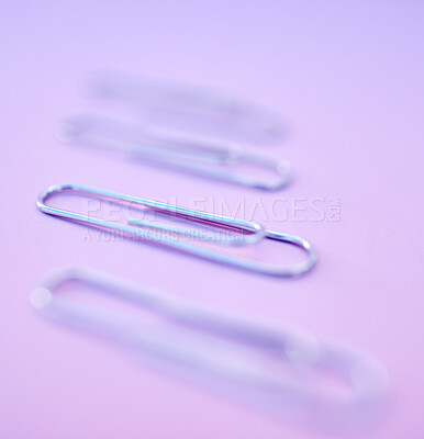 Buy stock photo Paperclip, filing and organization for documenting or attachment in studio on a purple background. Business, office and stationery with a metal clip for file or storage purposed on a color surface