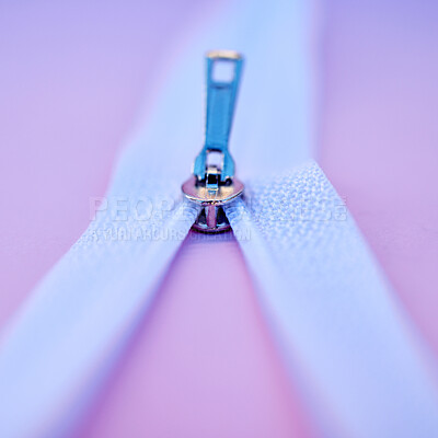 Closeup of a metal zip isolated on a pink background. Macro view of a zipper closing or being unzipped on fabric in a fashion, tailor, or seamstress studio. Clothing design and connection still life