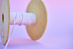 Closeup low angle view of a roll of pink cotton string thread isolated against a purple coloured background. Fabric design and texture still life in a fashion design studio. Clothing design and dressmaking creative concept
