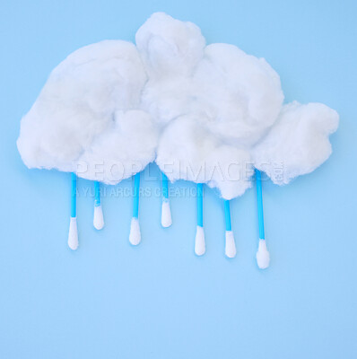 Earbuds and cotton wool shaped as a raincloud in studio, isolated against a blue background. Stay fresh and clean, take care of your personal hygiene. Perfect for ears and nose health and cleanliness