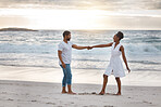 Playful african american couple spending a day at the sea together. Cheerful boyfriend and girlfriend dancing on the beach. Caring husband and wife bonding on the seashore