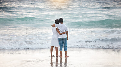 Buy stock photo Young african american couple spending a day at the sea together. Caring boyfriend and girlfriend watching the view on the beach. Loving husband and wife smiling while standing on the beach