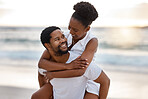 Young happy african American couple spending a day at the sea together. Cheerful boyfriend giving his girlfriend a piggyback on the beach. Caring husband and wife bonding on the seashore