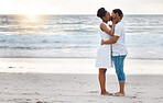 Fullbody of a happy african American couple spending a day at the sea together. Content boyfriend and girlfriend kissing lovingly on the beach. Caring husband and wife bonding on the seashore
