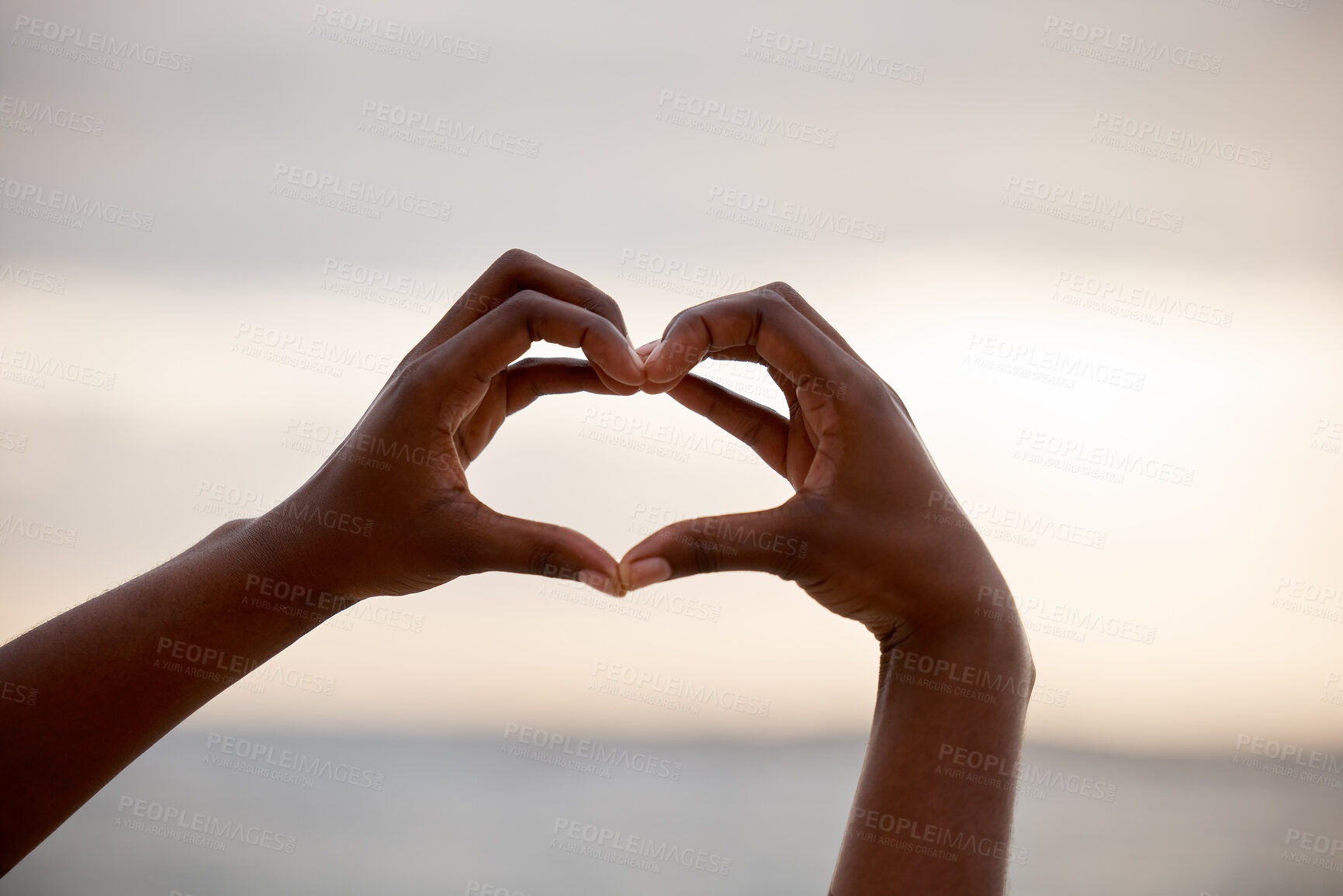 Buy stock photo Hand, heart and love sign at the beach with romantic, emoji and happiness hands gesture. Outdoor, sea and ocean with person holding romance, loving and valentines sign on holiday in nature at sunset
