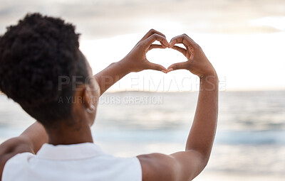 Buy stock photo Woman hand, heart and love sign at the beach with romantic, emoji and happiness hands gesture. Outdoor, sea and ocean with female person back with kindness sign on holiday in nature at sunset