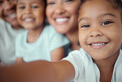 Buy stock photo Close up of adorable little girl holding phone and taking selfie or recording funny video with her family. Happy mixed race family with two children and parents posing together for a family picture on a mobile phone