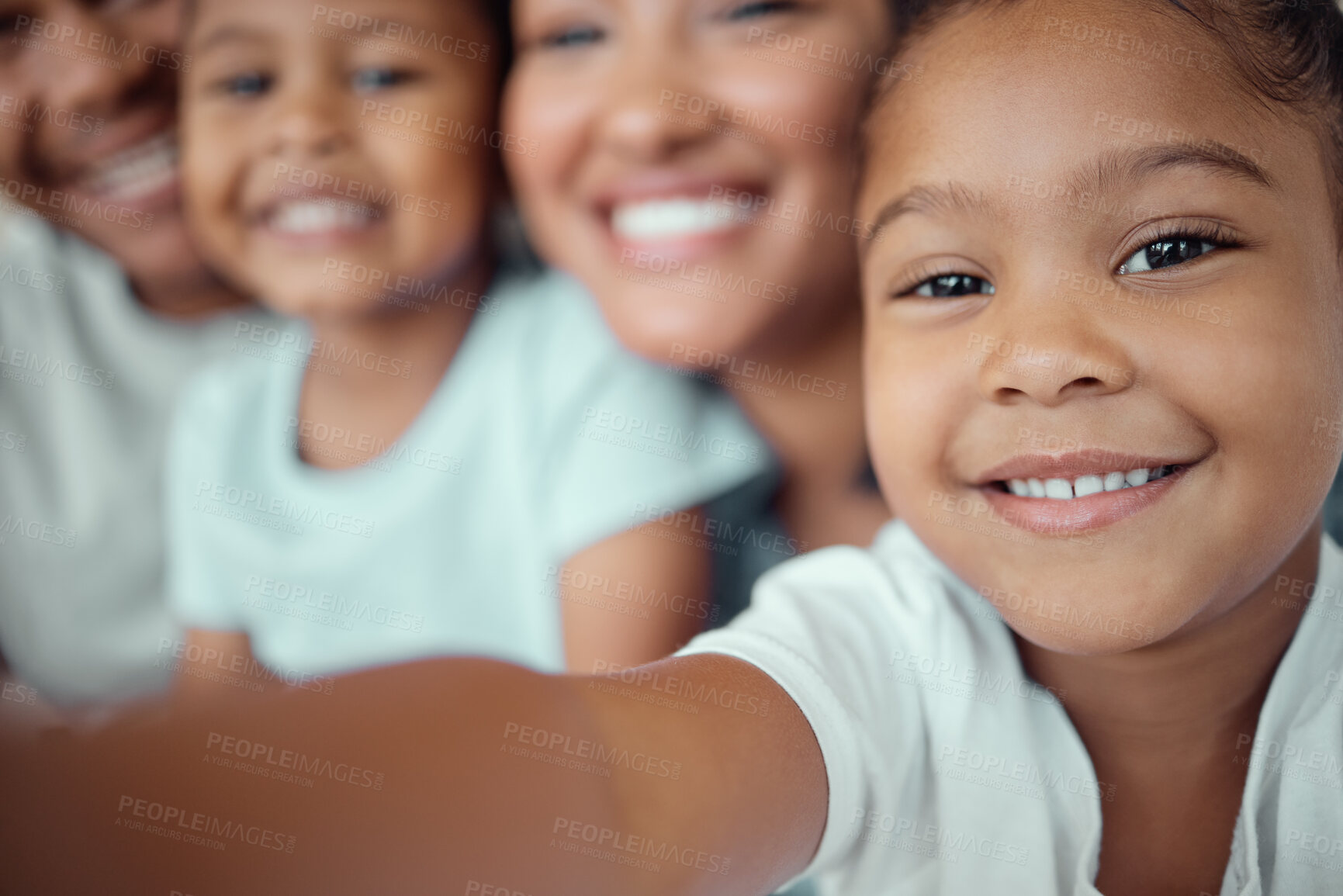 Buy stock photo Close up of adorable little girl holding phone and taking selfie or recording funny video with her family. Happy mixed race family with two children and parents posing together for a family picture on a mobile phone