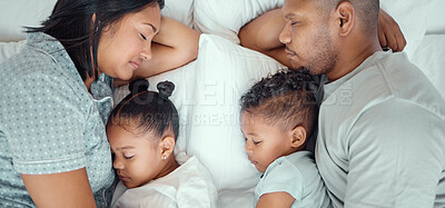 Happy family with two children sleeping together in their parents bed, from above. Loving parents cuddling two little kids for bedtime. Adorable girl and boy taking a nap and rest with mom and dad