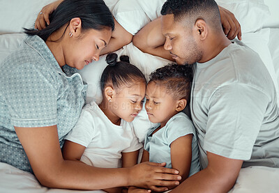 Happy family with two children sleeping together in their parents bed, from above. Loving parents cuddling two little kids for bedtime. Adorable girl and boy taking a nap and rest with mom and dad