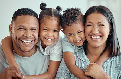 Buy stock photo Portrait of a happy young mixed race family with two children wearing pyjamas and sitting at home together. Cute little girl and boy embracing their mother and father from behind