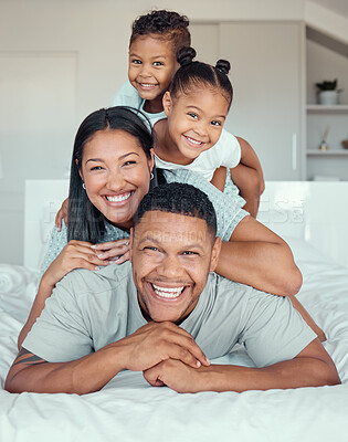 Buy stock photo Portrait of a cheerful family lying on top of their father on a bed. Two children and wife lying on dads back laughing and having fun. Mixed race couple bonding with their son and daughter. Dad is the backbone of the family and supports everyone