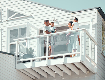 Buy stock photo Happy mixed race family with two children wearing pyjamas while standing on balcony at their new house or while on holiday. Young parents talking while holding their son and daughter outside
