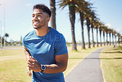 Fit hispanic athlete wearing a smartwatch to track his progress while running outside. Athletic man in a park. Smiling man exercising outdoors. Mixed race man feeling positive while doing cardio