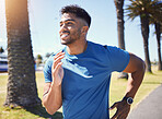 Happy smiling young mixed race fit man enjoying a run in a park during summer alone. One cheerful hispanic male smiling, exercising and jogging in nature. Dedicated to fitness and a healthy lifestyle