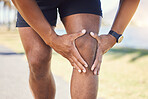 Closeup of unknown fit active mixed race man holding his knee in pain. Unrecognizable athlete suffering from discomfort from a bad knee injury. Arthritis causing him to hold his leg while exercising