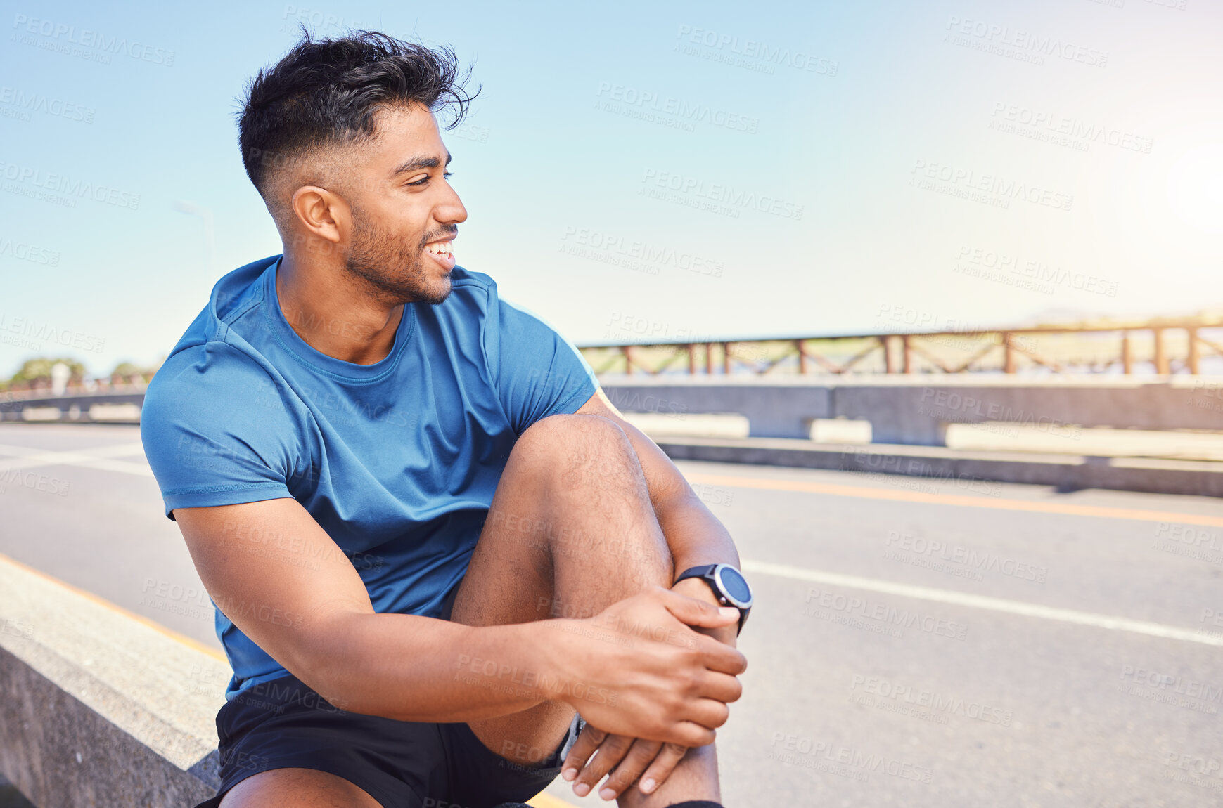 Buy stock photo Happy smiling young mixed race fit man enjoying a break from exercising outside. Hispanic male sitting down before starting his cardio workout outdoors. Positive and his fitness and heart health