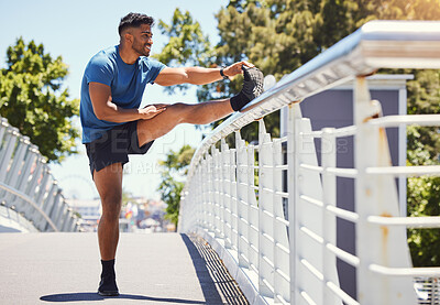 Buy stock photo Fit athletic mixed race man stretching on a bridge in the city during his workout. Young hispanic man doing warm up exercises outdoors on a sunny day. Warming up before starting is endurace and cardio