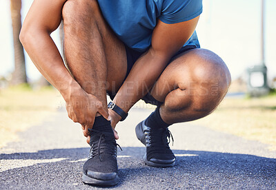 Buy stock photo Closeup of active mixed race man holding his ankle in pain while out for a run. Unknown athlete suffering from discomfort from a sprained ankle or sports injury. Exercising comes with the risk of pain