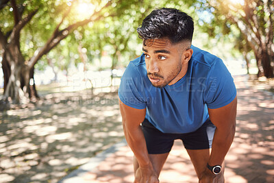 Buy stock photo Exhausted young mixed race man standing with hands on his knees while taking a break from exercising in a park trying to stay fit. Athletic hispanic male resting and catching his breath after a run