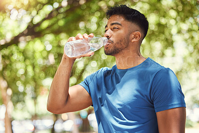 Buy stock photo Fitness, man or runner drinking water outdoor for exercise, training or running at a park. Indian male athlete in nature for a workout, run and break to drink from a bottle for health and wellness