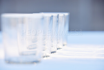 Pics of Closeup of a row of clear empty drinking glasses reflecting sunlight. Set of transparent glasses for drinks, whisky or other beverages on a table, stock photo, images and stock photography PeopleImages.com. Picture 2497027