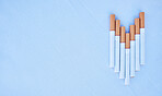 Studio shot of cigarettes in a line shaped like an arrow or arrow pointing down isolated against a blue background. Tobacco and nicotine are addictive and harmful and will cause your health to decline