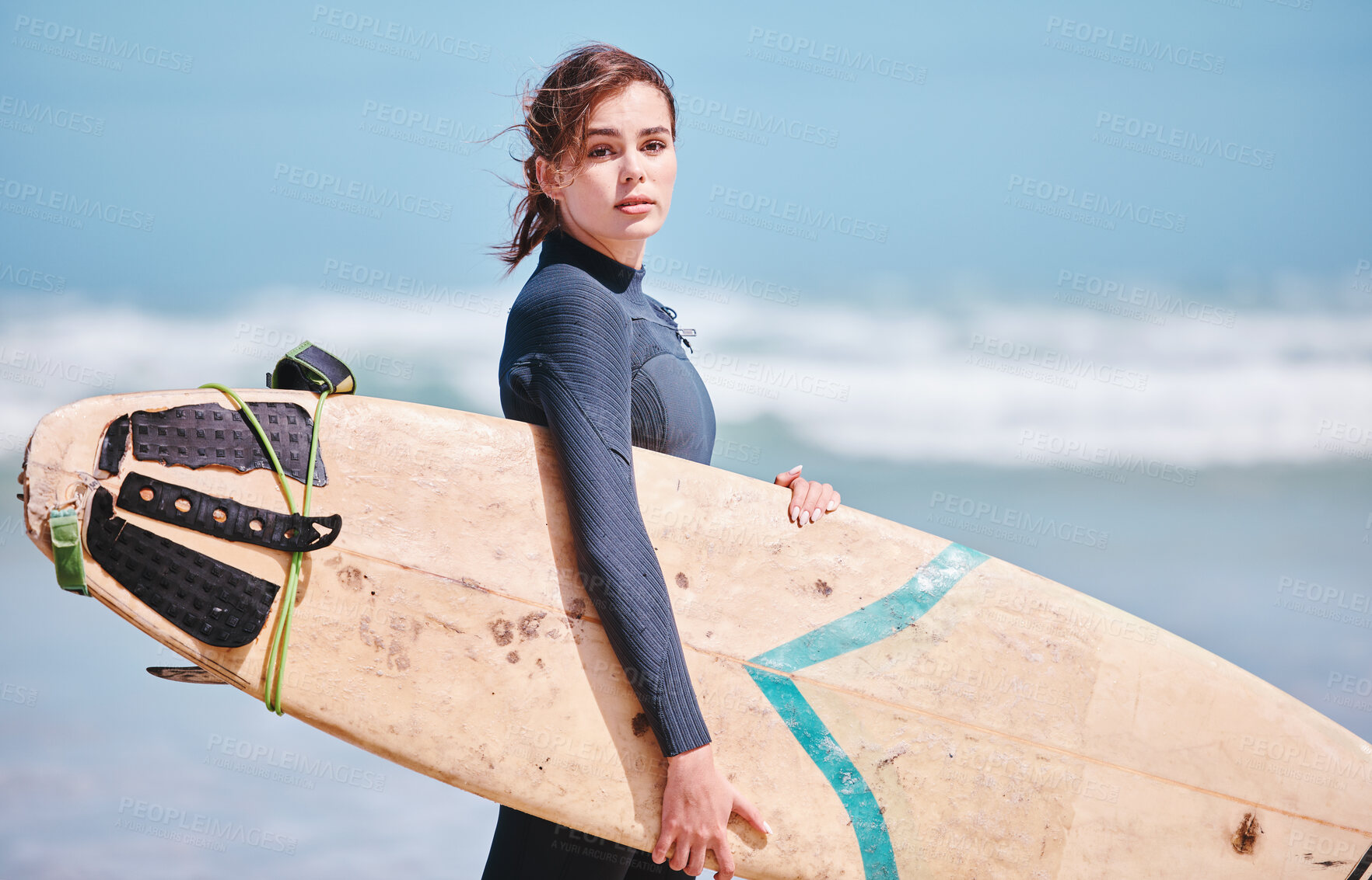 Buy stock photo Portrait of beautiful caucasian woman standing alone on a beach, holding a surfboard and wearing a wetsuit before surfing in the sea. Active and athletic woman getting ready to surf waves as a hobby